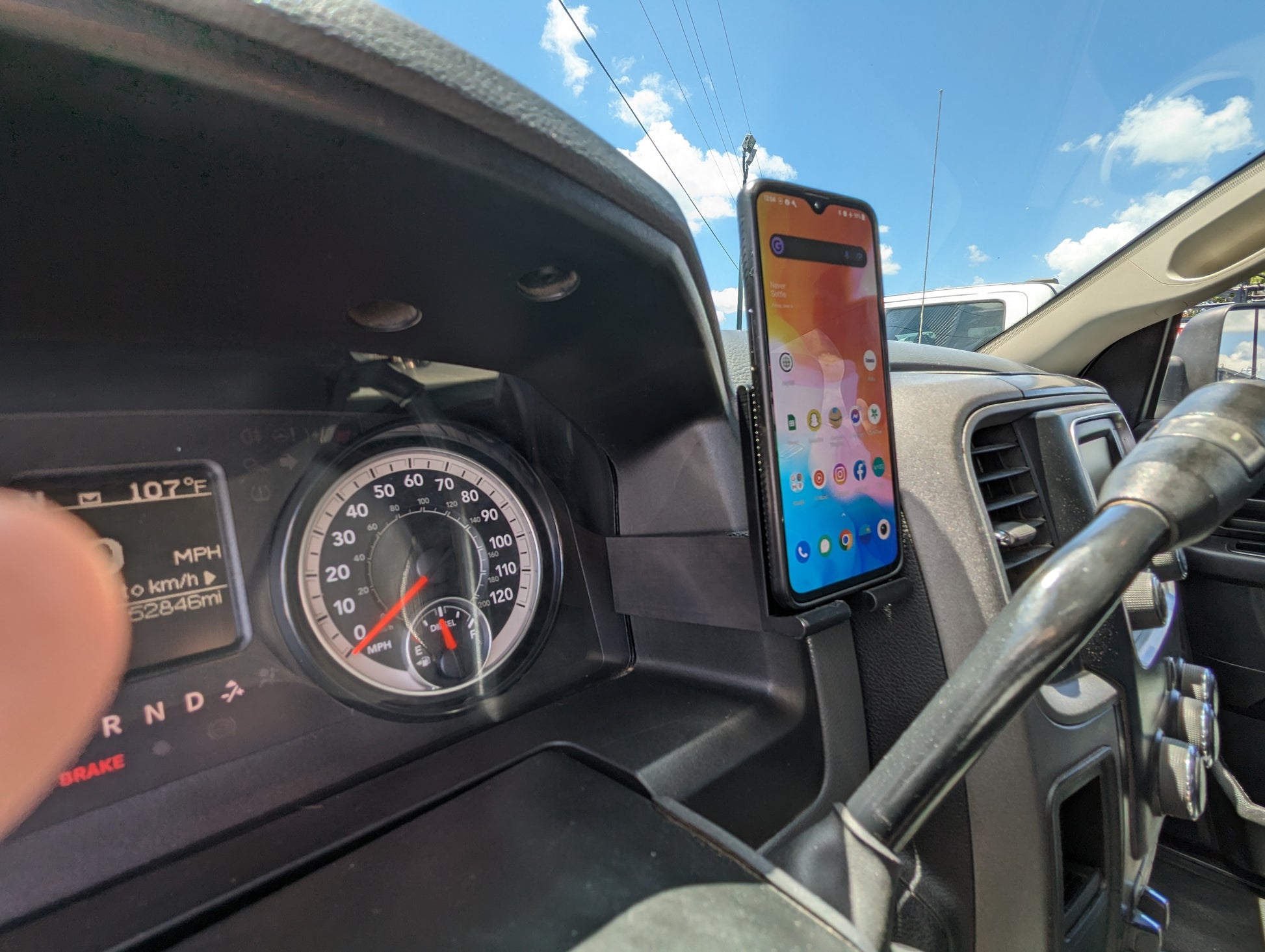 A black phone mount for a Dodge Ram vehicle, showing the mount attached to the dashboard with a smartphone placed in it.