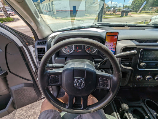 A black phone mount for a Dodge Ram vehicle, showing the mount attached to the dashboard with a smartphone placed in it.